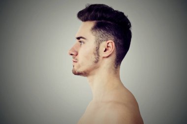 Genç yan görünüm fit vücut uzak gri arka plan üzerinde seyir ile yakışıklı adam sakallı