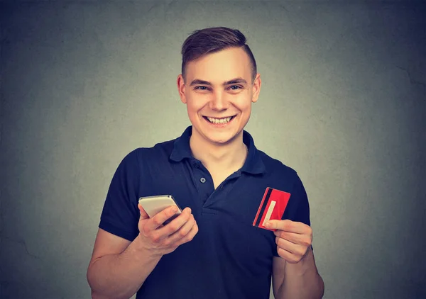 Pohledný Mladý Muž Drží Kreditní Karty Mobilního Telefonu Nadšená Pohodlné — Stock fotografie