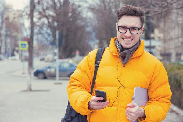 Όμορφος Νεαρός Κίτρινο Παλτό Κρατώντας Smartphone Και Tablet Περπατώντας Στον — Φωτογραφία Αρχείου