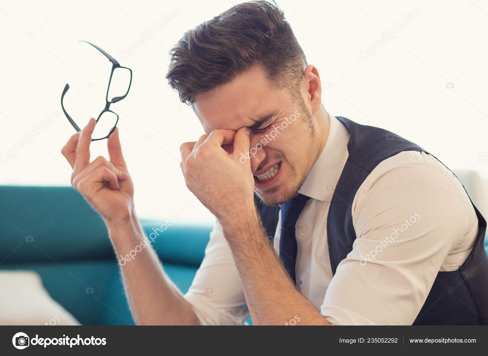 Young Man Rubbing Nose Bridge While Holding Eyeglasses Suffering Eyes