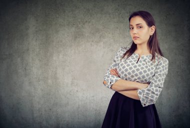 Genç mağrur kadın kolları gri arka plan üzerinde çarpı işareti olan ayakta kendine aşırı güvenen arıyor