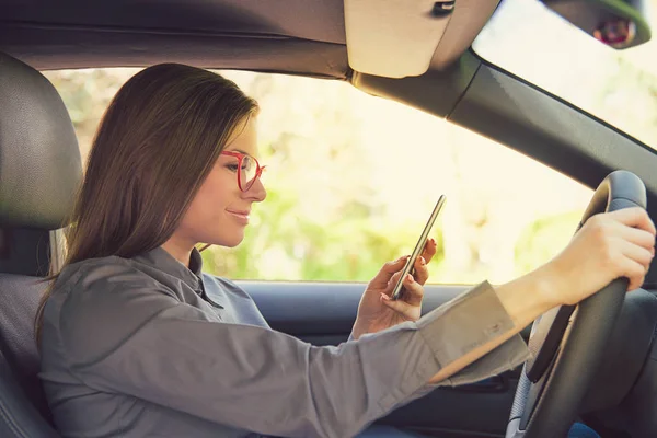 Vista Lateral Mujer Joven Distraída Gafas Con Smartphone Mientras Conduce — Foto de Stock