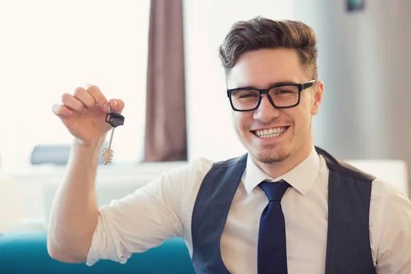 Jovem Sorrindo Homem Óculos Segurando Chave Nova Casa Sentada Sofá — Fotografia de Stock