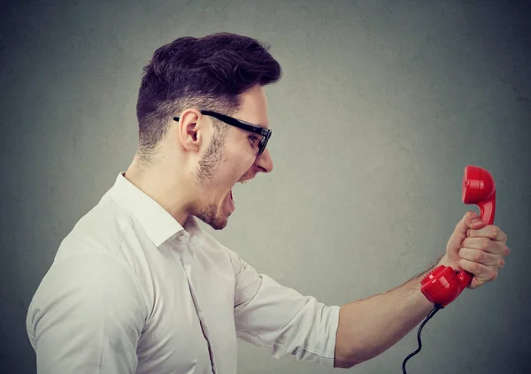 Angry businessman yelling on a red telephone — Stock Photo, Image