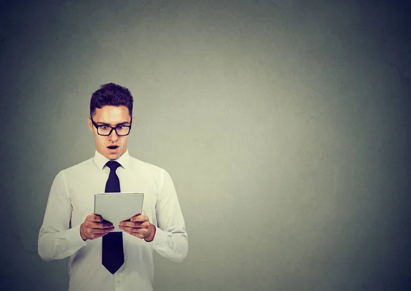 Joven hombre de negocios sorprendido en gafas usando una tableta — Foto de Stock