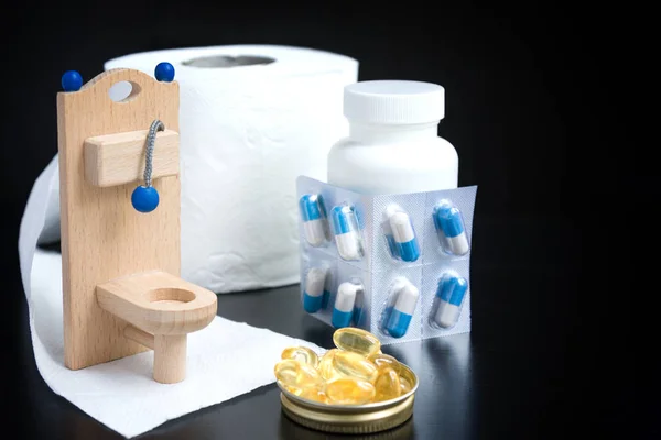 Wooden toy toilet, capsules and paper on black