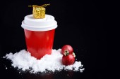 Káva jít v červené pohár a vánoční ozdoby na černém pozadí