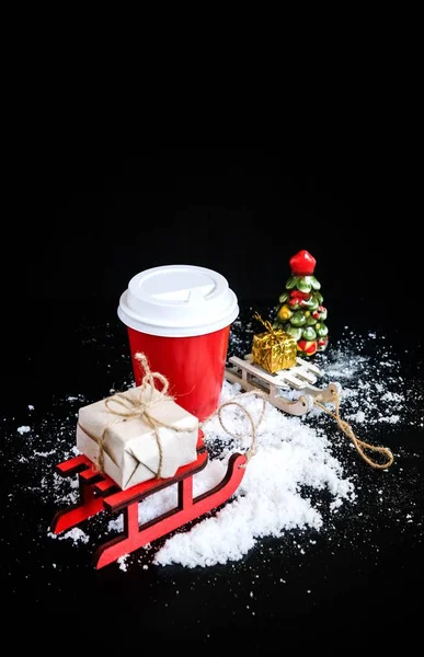 Coffee to go in red cup and christmas decorations on black