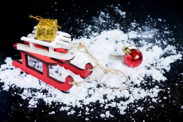 Wooden sledge with gifts on black background with snow