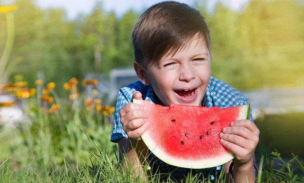Divertente ragazzo mangia anguria all'aperto nel parco estivo — Foto Stock