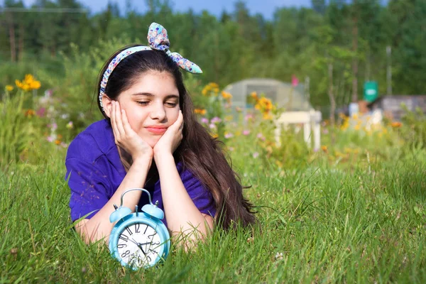 Girl with alarm clock in summer garden — Stock Photo, Image