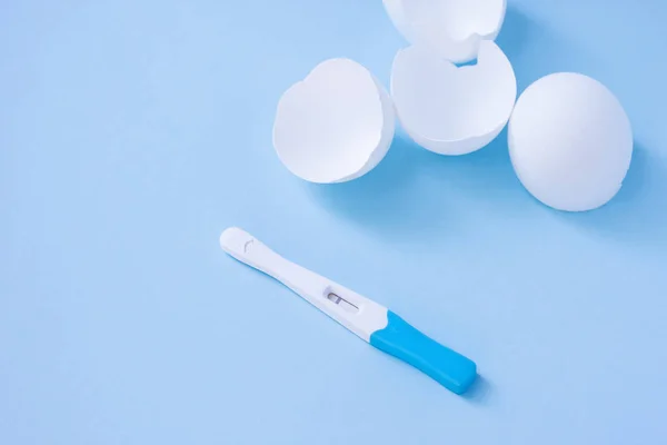 Infertilidade. Teste de gravidez negativo e casca de ovo no azul — Fotografia de Stock