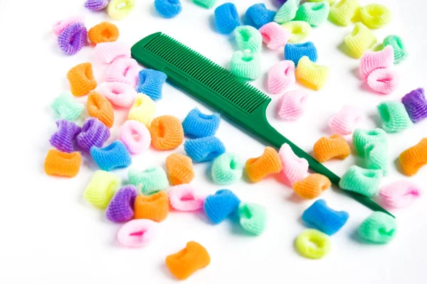 Green plastic comb and bright multi-colored scrunchies on white — Stock Photo, Image