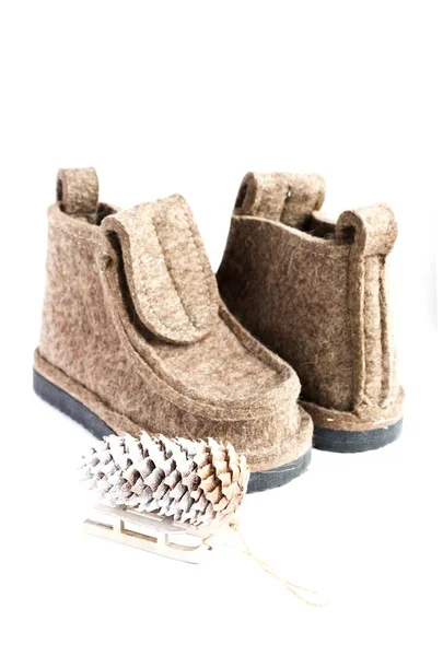 Piccola slitta e cono contro stivali di feltro invernali su bianco — Foto Stock