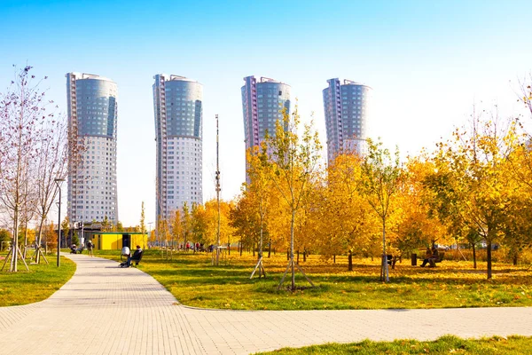 Les gens marchent dans le parc paysager de la ville "champ de Khodynskoe" et les gratte-ciel modernes, Moscou, Russie. Il a ouvert ses portes en septembre 2018. La superficie totale du parc est d'environ 25 hectares — Photo