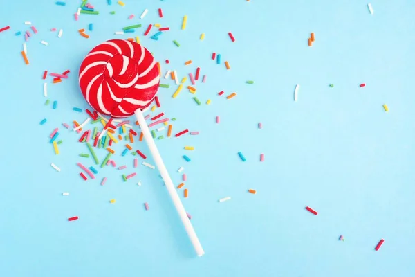 Colorful lollipop and confetti on blue — Stock Photo, Image