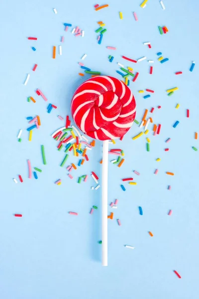 Colorful lollipop and confetti on blue — Stock Photo, Image