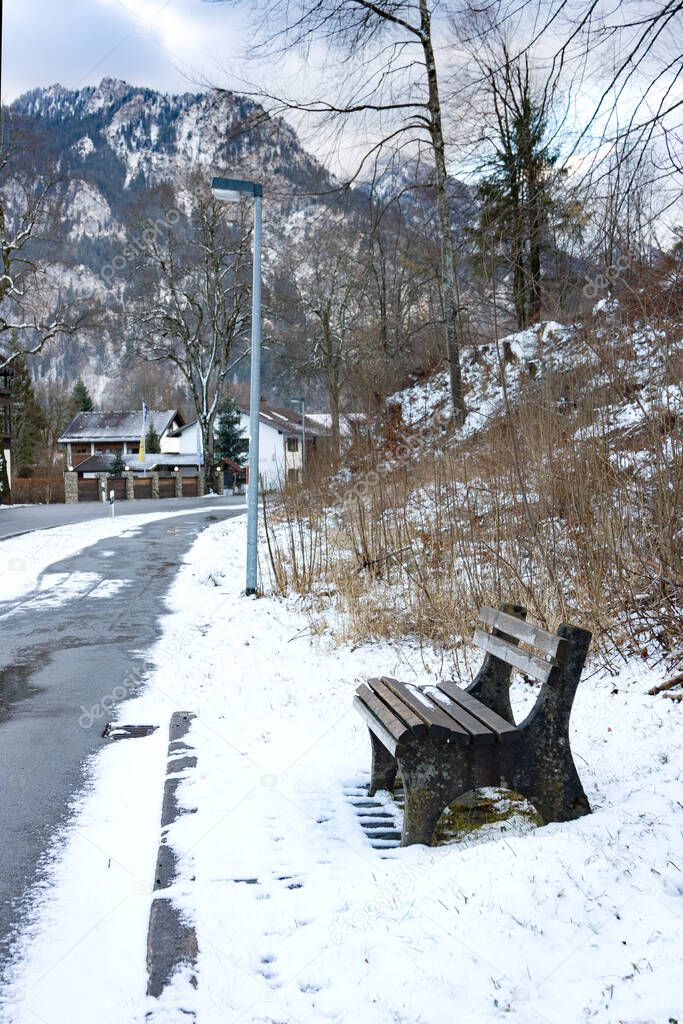 Wooden empty bench against Alps in winter day. Schwangau, Bavaria, Germany