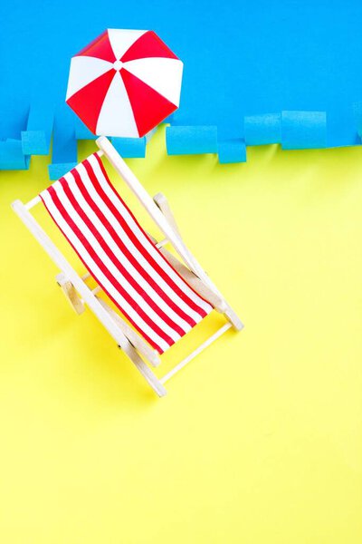 Striped red deck chair near sea. Toy recliner on blue and yellow background. Concept summer rest. Vacations.