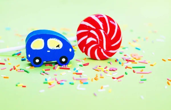 Toy Wooden Blue Car Lolipop Confetti Green Backgroun Sweet Chilhood — Stock Photo, Image
