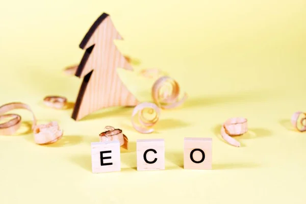 Wooden fur-tree, curled shavings and word eco on yellow. Eco toys. Save the forests, awareness concept. Environmentally friendly investments. Sawdust of woodworking industry. Sawmill, carpentry