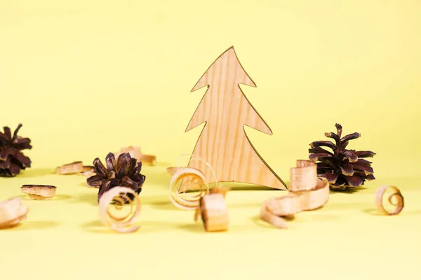 Wooden fur-tree and curled shavings on yellow backround. Eco toys. Save the forests, awareness concept. Environmentally friendly investments. Sawdust of woodworking industry. Sawmill, carpentry