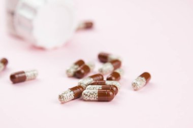 Pembe üzerinde kahverengi çözünür kapsüller. Bitkisel ilaçlar. Kapsülde alternatif tıp.