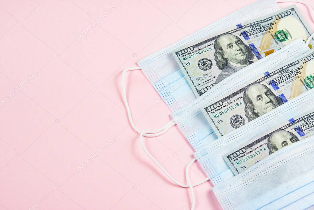 Blue medical masks and dollars on pink.Helping poor countries with money and masks.Financial crisis due to coronavirus.Cash payments to doctors.Expensive hospital services.Sponsoring medical research.