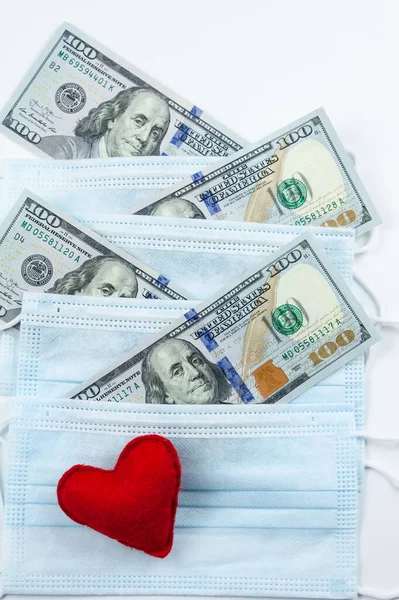 ピンクの赤いハート 医療用マスクとドル お金とマスクで貧しい国を支援します コロナウイルスによる金融危機医師への現金支払い 医学研究 ロイヤリティフリーのストック画像