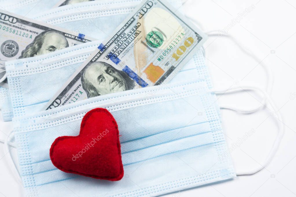 Red heart,medical masks and dollars on pink.Helping poor countries with money and masks.Financial crisis due to coronavirus.Cash payments to doctors.Expensive hospital services. Medical research.