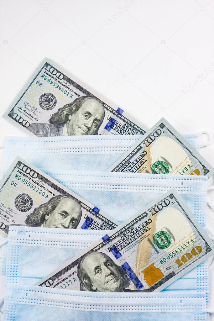 Blue medical masks and dollars on pink.Helping poor countries with money and masks.Financial crisis due to coronavirus.Cash payments to doctors.Expensive hospital services.Sponsoring medical research.