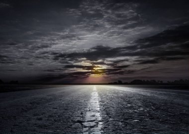 Asfalt yolun içinde belgili tanımlık geçmiş gün batımının büyüleyici manzarasına. Yolun buğday ve bozkır çim alanlar arasında. Ufukta güzel gün batımı