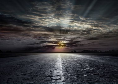 Asfalt yolun içinde belgili tanımlık geçmiş gün batımının büyüleyici manzarasına. Yolun buğday ve bozkır çim alanlar arasında. Ufukta güzel gün batımı