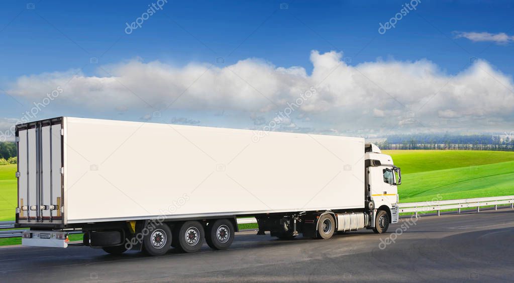 White trailer on the highway, against the background of a green 