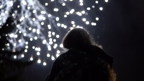 La chica toma fotos de fuegos artificiales en un teléfono móvil. Silueta en el fondo del cielo iluminada por luces . — Vídeos de Stock