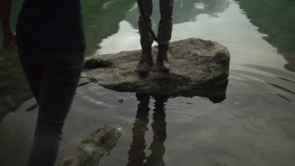 Touristin überquert den Fluss auf der anderen Seite der glitschigen Felsen — Stockvideo