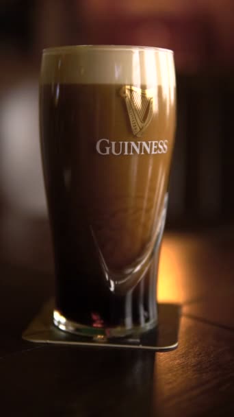 Pyatigorsk, Rusland-oktober 8, 2018: het originele glas Guinness bier op tafel ligt, het schuim langzaam afwikkelt. Verticale video 's Stockvideo