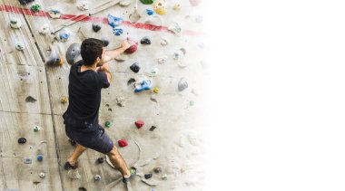 Yapay duvarda kapalı bir adam pratik dağcılık. Aktif yaşam tarzı ve bouldering kavramı kopya alanı ile