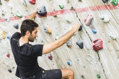 İçerideki yapay duvarda kaya tırmanışı pratiği yapan bir adam. Etkin yaşam tarzı ve kayalık kavramı.