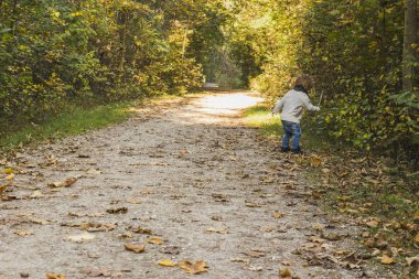 Sonbaharda bir orman yolu üzerinde oynayan bebek