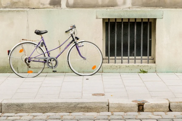 Bicicleta velha inclinada na parede no edifício da cidade — Fotografia de Stock