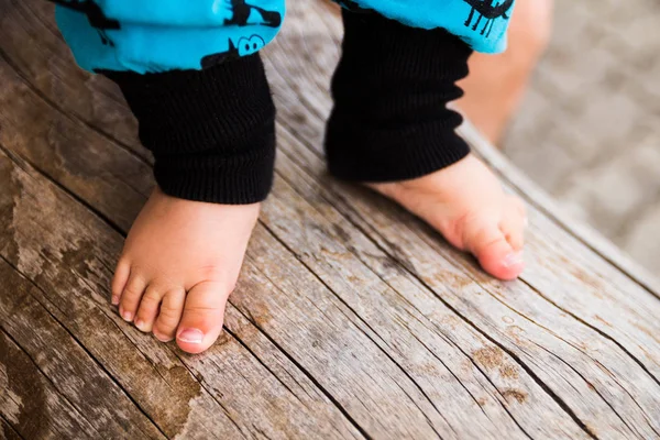 Bebê com os pés descalços no tronco da árvore — Fotografia de Stock