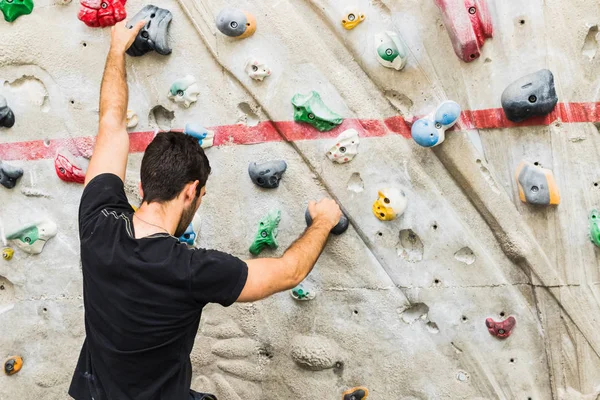 Hombre practicando escalada en roca en paredes artificiales en interiores. Activo —  Fotos de Stock