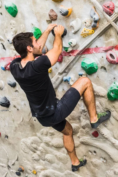 Hombre practicando escalada en roca en paredes artificiales en interiores. Activo —  Fotos de Stock