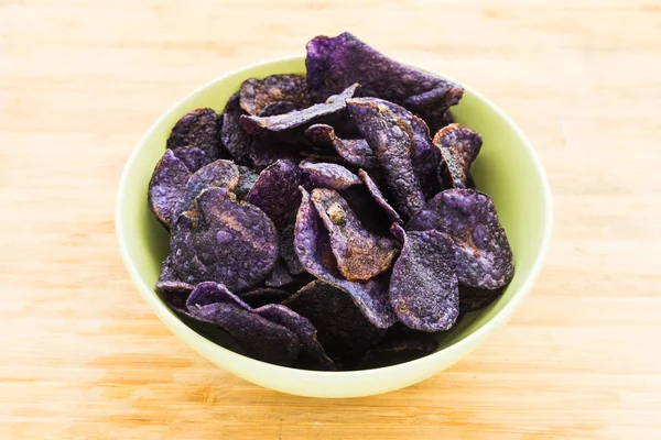 Heap of purple potato chips on wooden background — Stock Photo, Image