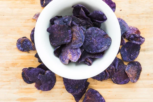 Heap of purple potato chips on wooden background — Stock Photo, Image