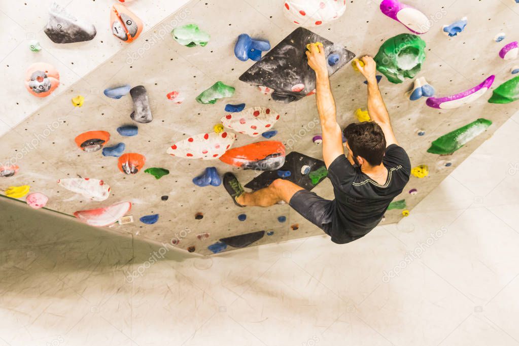 Man practicing rock climbing on artificial wall indoors. Active 