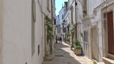 İtalya, bölge, Locorotondo, tarihi merkezi Ortaçağ kökenli dar sokaklarında oluşan ve dar sokaklar, badanalı evler ve çiçeklerle Puglia. Turistler. Zaman atlamalı