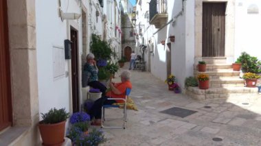 İtalya, bölge, Locorotondo, tarihi merkezi Ortaçağ kökenli dar sokaklarında oluşan ve dar sokaklar, badanalı evler ve çiçeklerle Puglia. Turistler. Zaman atlamalı