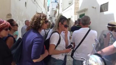 İtalya, bölge, Locorotondo, tarihi merkezi Ortaçağ kökenli dar sokaklarında oluşan ve dar sokaklar, badanalı evler ve çiçeklerle Puglia. Turistler. Zaman atlamalı